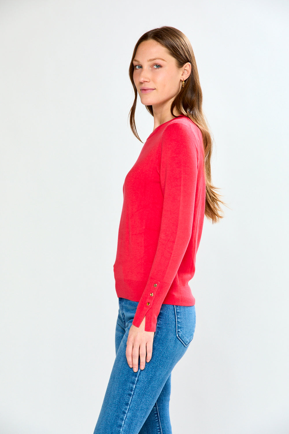 Woman wearing a pink sweater and light blue jeans on a white background