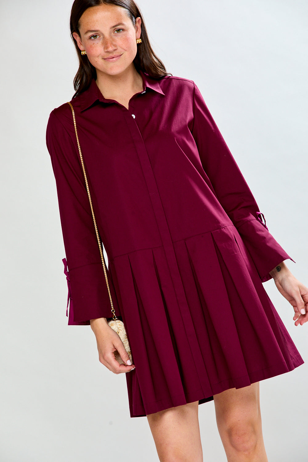 Woman wearing a raisin dress with long sleeves on a white background