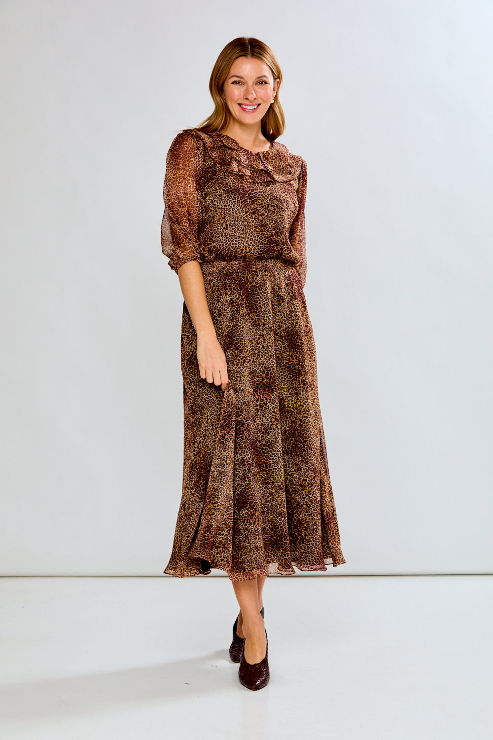 Woman wearing a brown patterned dress against a white background