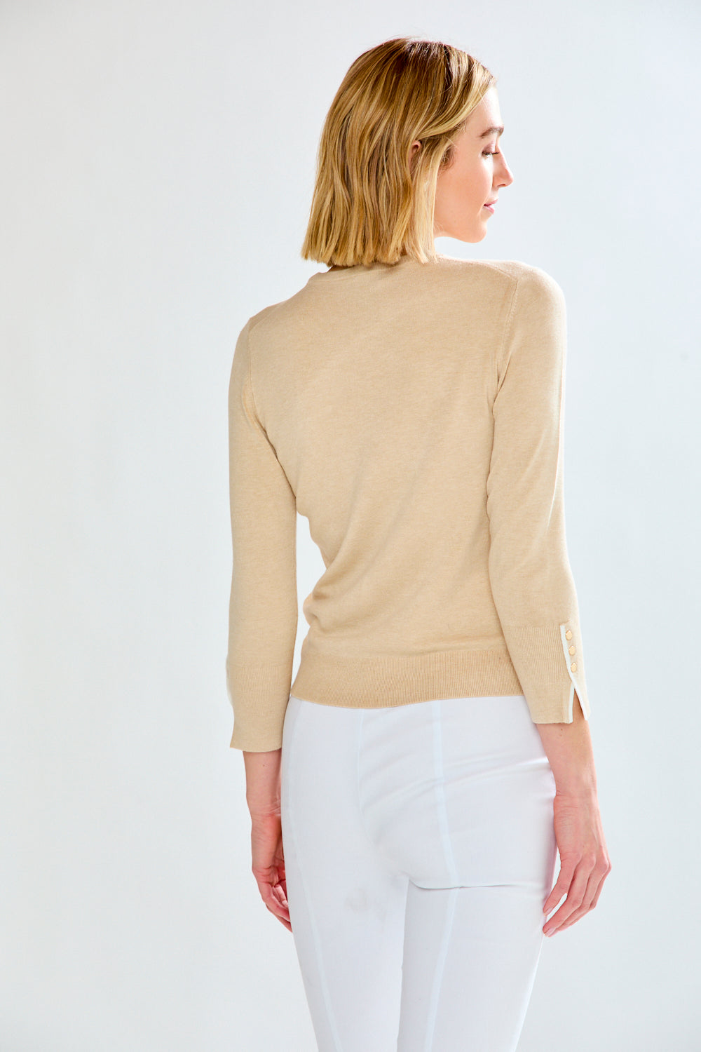 woman in tan sweater and white pants
