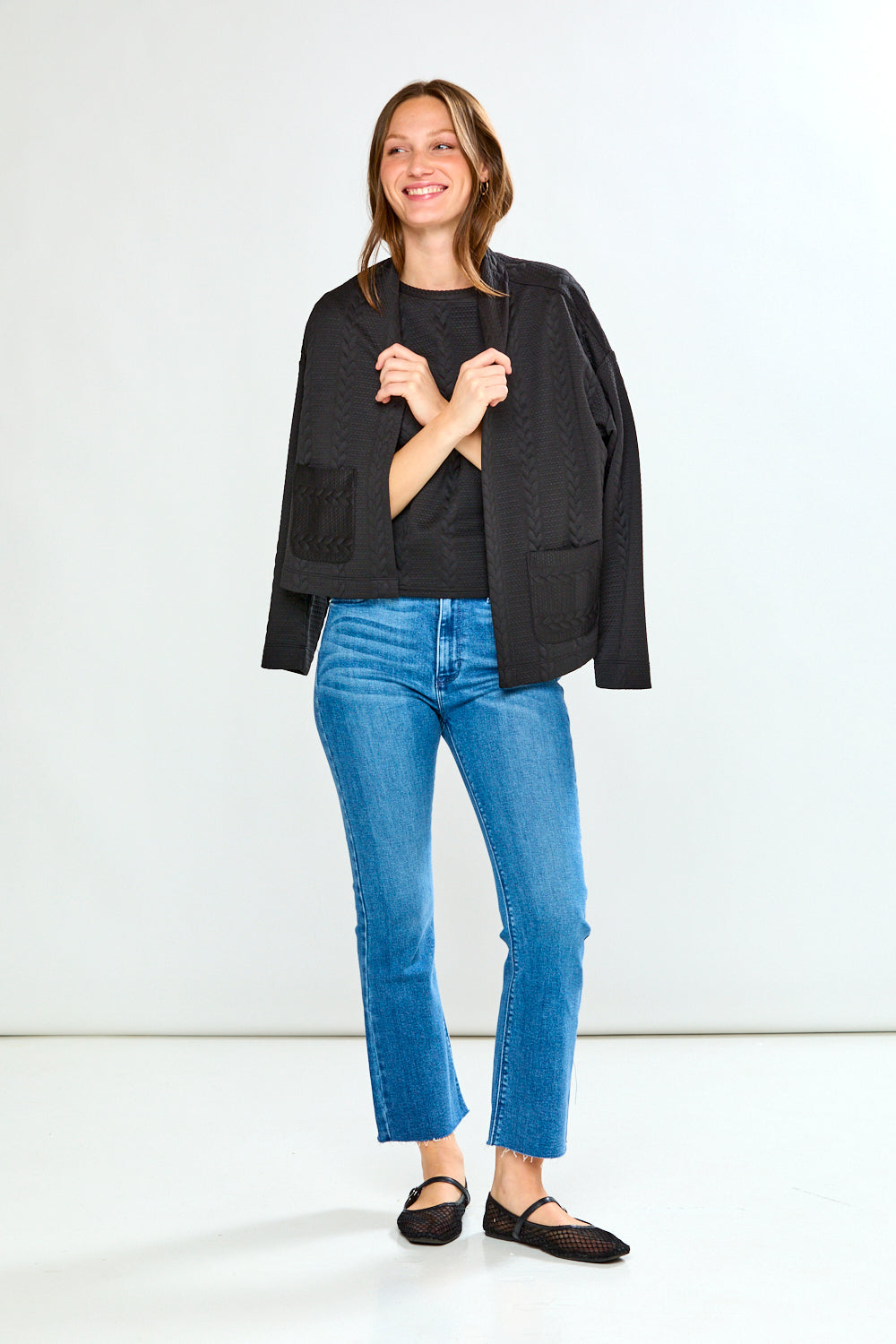 Woman wearing a black jacket and blue jeans on a white background