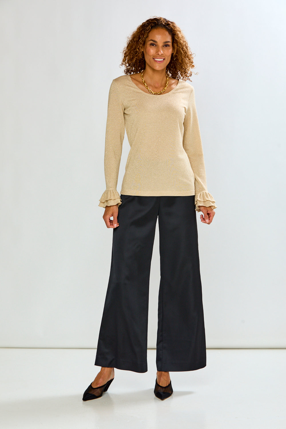 The Reyna Pant - Black shown as sophisticated wide leg women's pants styled with a beige long sleeve top and black heels for a timeless look