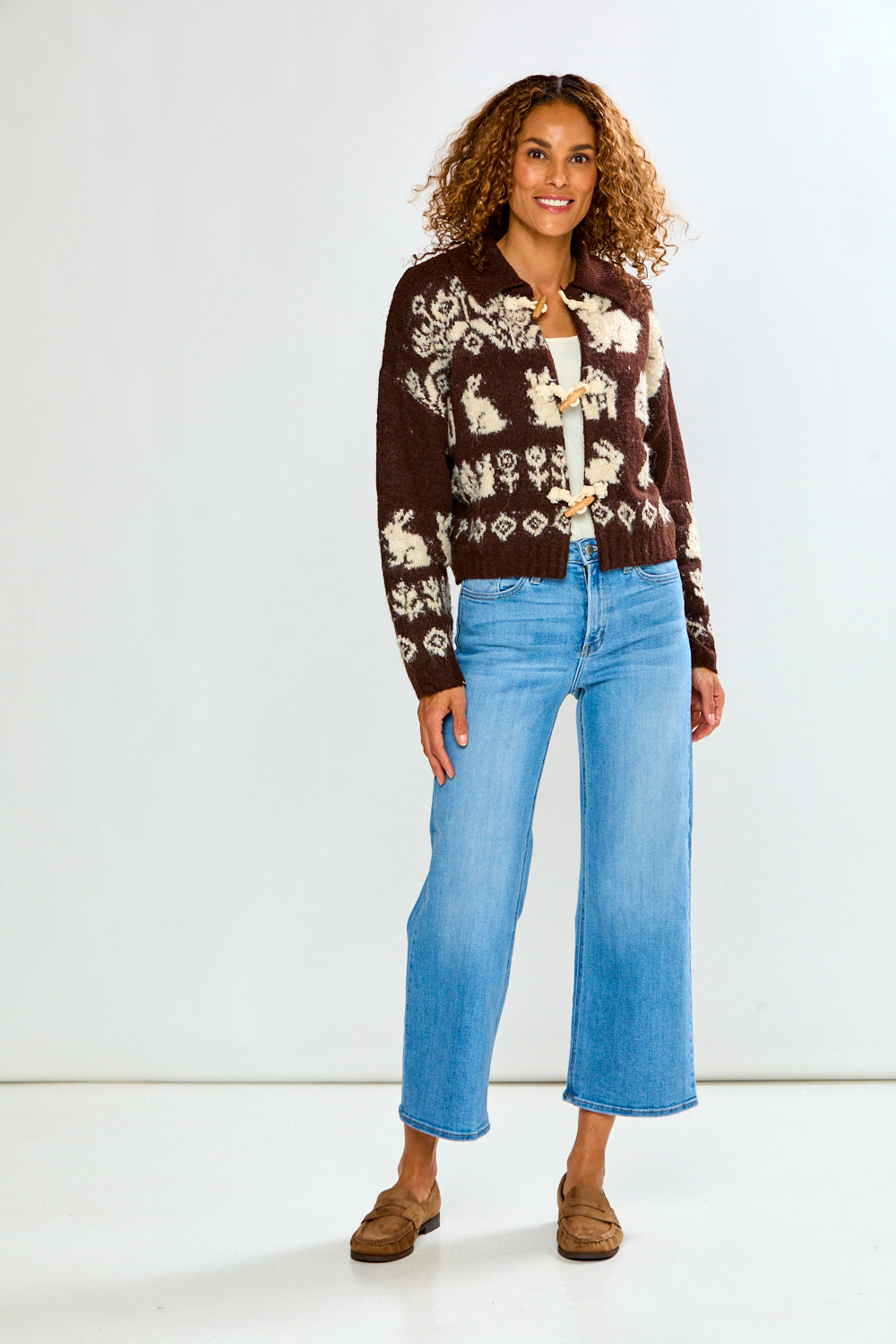 The Bunny Toggle Sweater - Brown Multi in brown patterned knit with toggle closures styled with light blue wide leg jeans and brown loafers on a model