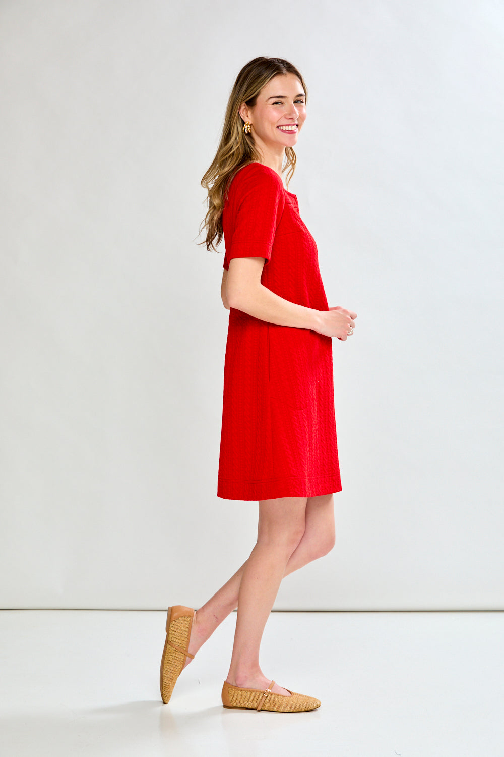 Woman wearing a red dress standing against a white background