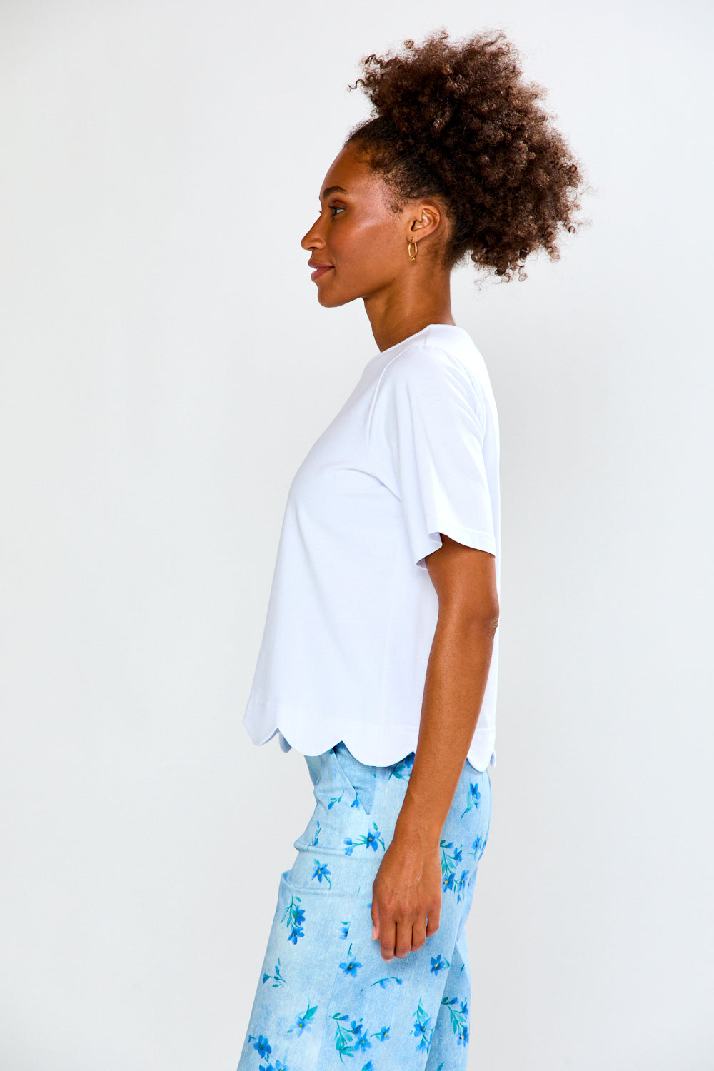 Person wearing a white t-shirt and light blue floral pants against a plain background