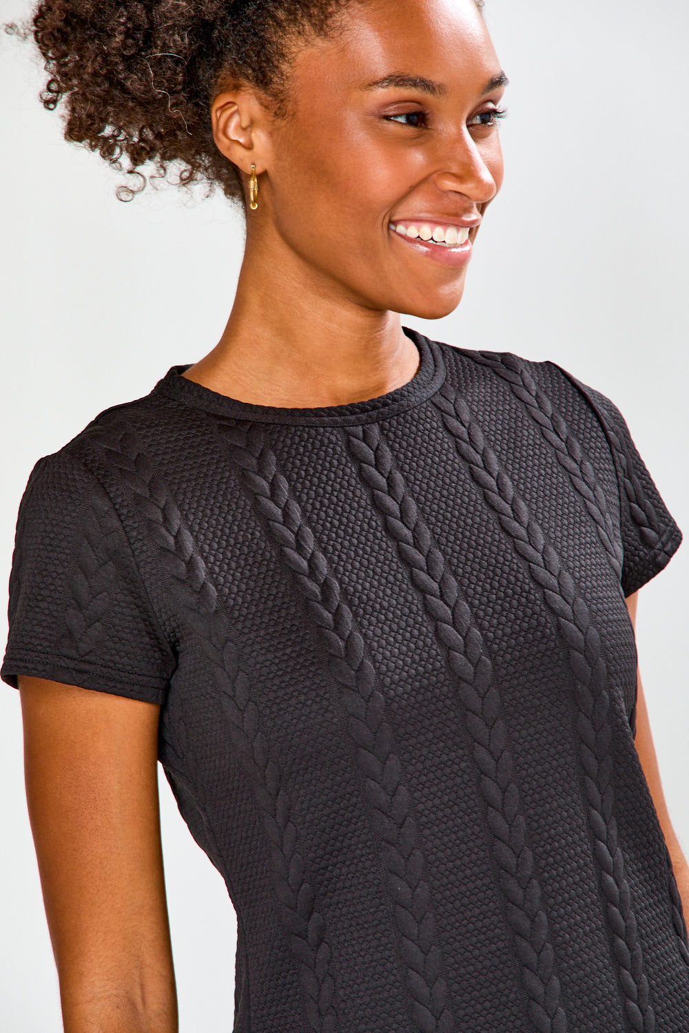 Woman wearing a black textured top and blue pants on a white background