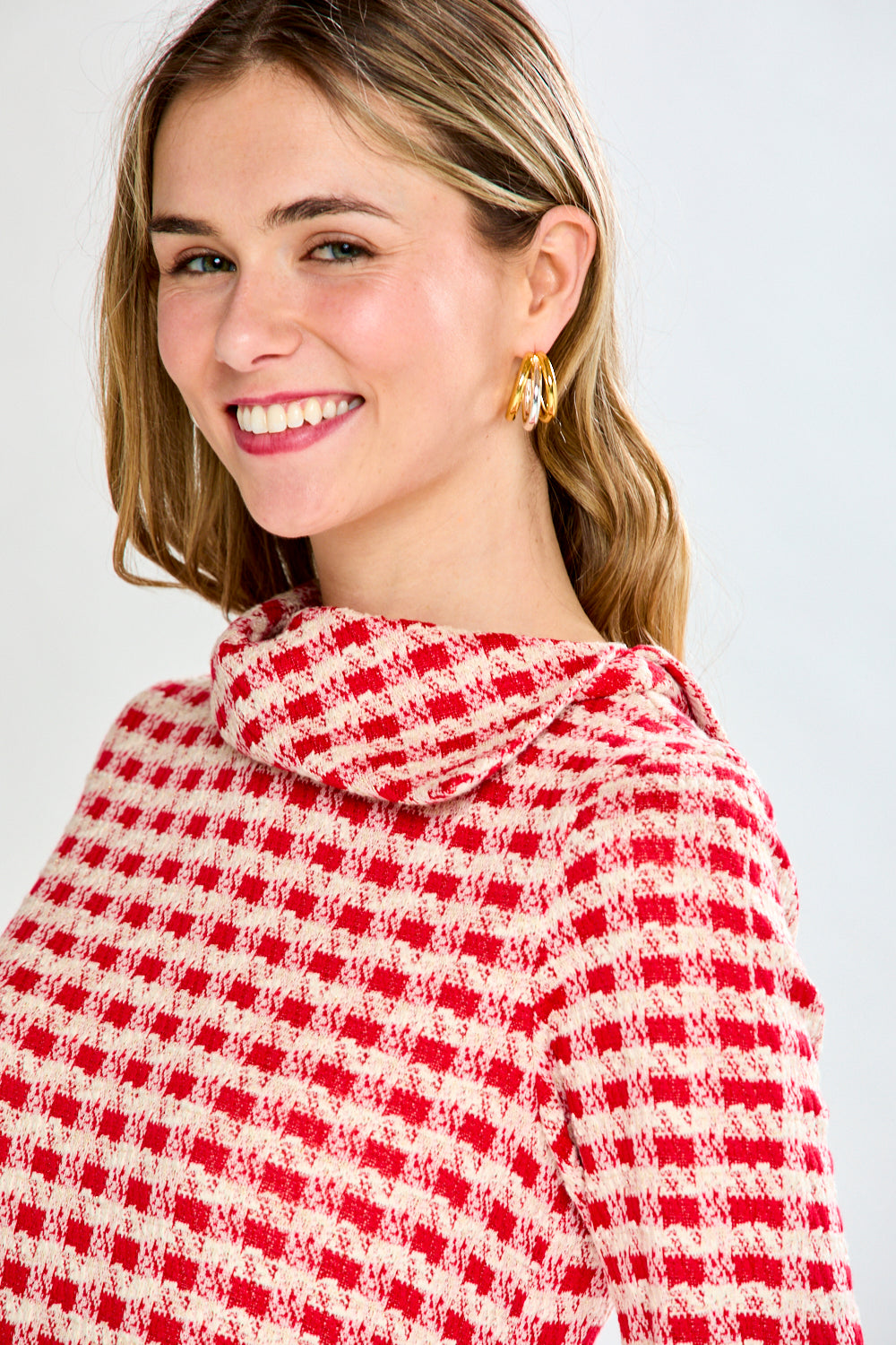 Woman wearing a red and white checkered sweater against a plain background