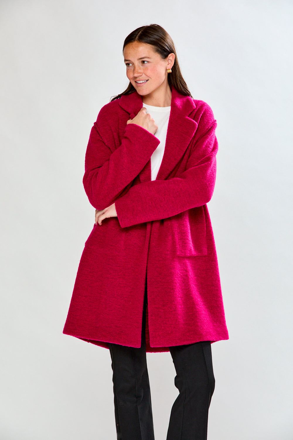 Woman wearing a bright pink coat against a white background