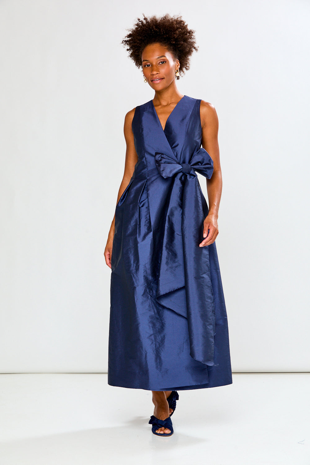 Woman wearing a blue dress with a bow detail on a white background