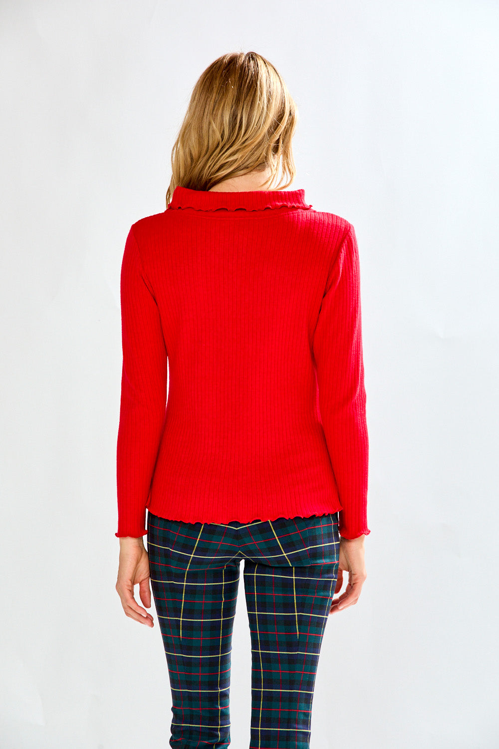 Woman wearing a red sweater and plaid pants on a white background