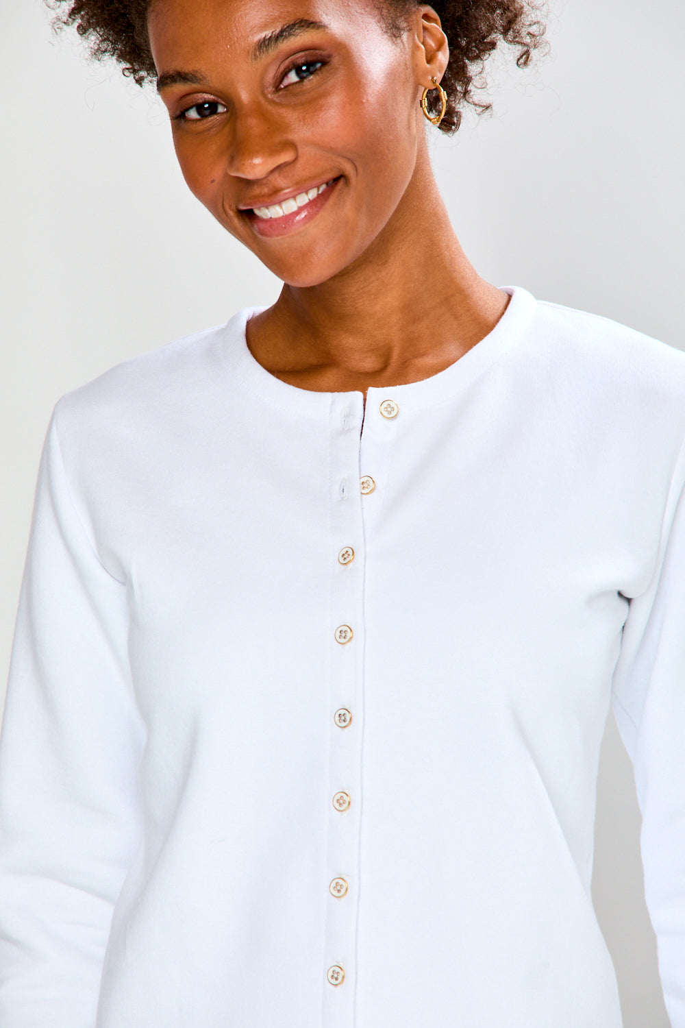 Woman wearing a white button-up shirt against a plain background