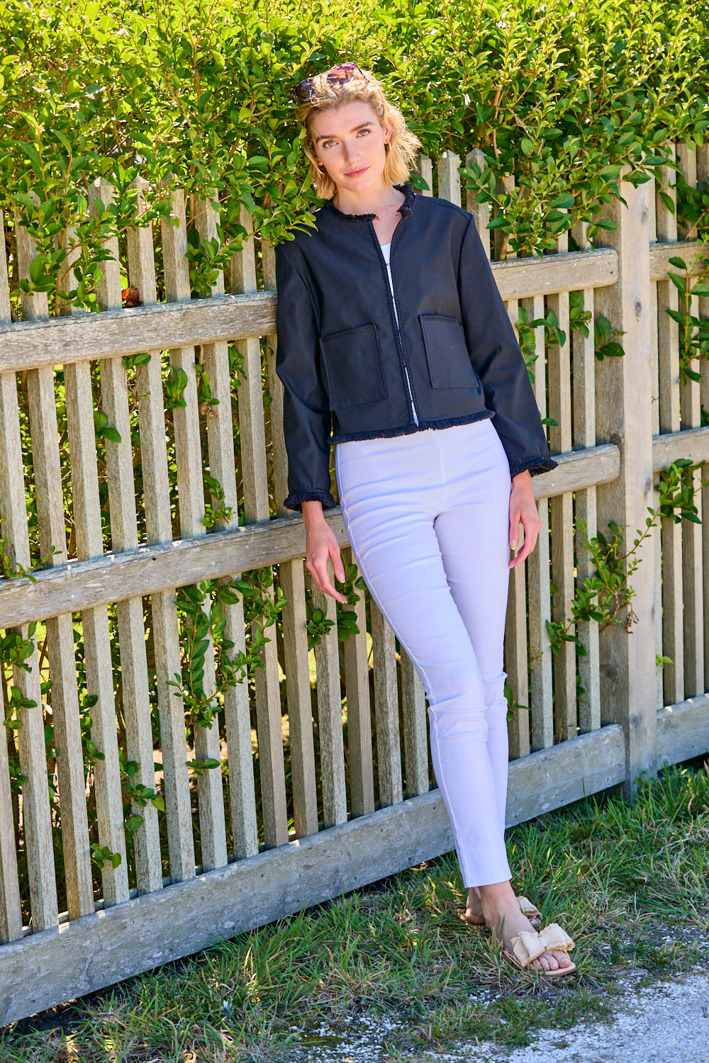 Woman wearing a black jacket with fringe detail and white pants