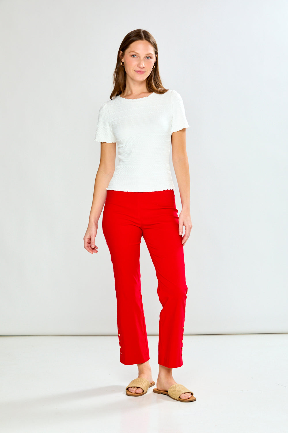 Woman wearing a white top and red pants on a white background