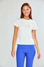 Woman wearing a white t-shirt and blue pants against a plain background