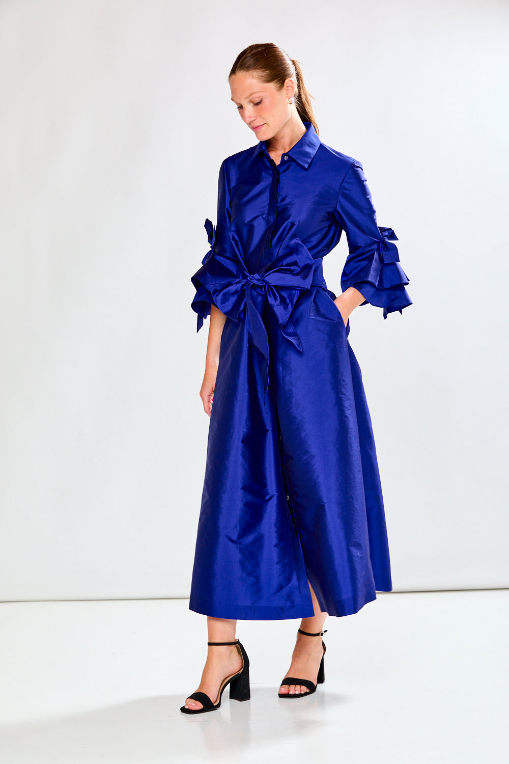 Woman wearing a blue dress with a large bow on a white background
