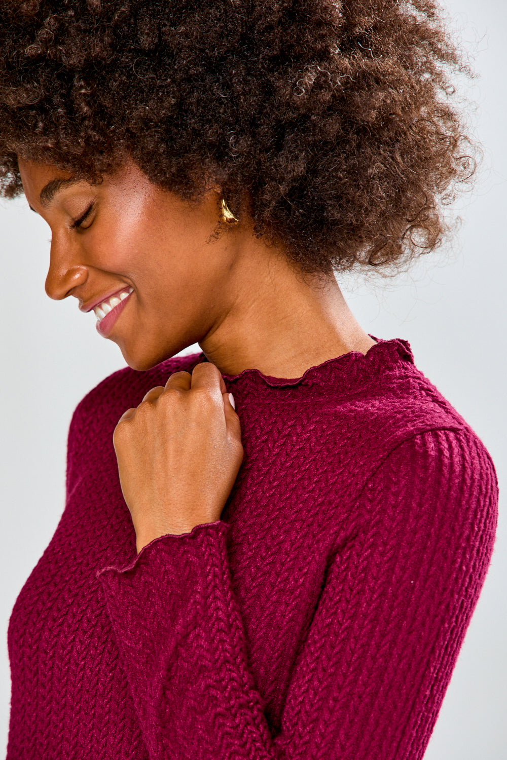 Woman wearing a burgundy shirt and black pants against a white background