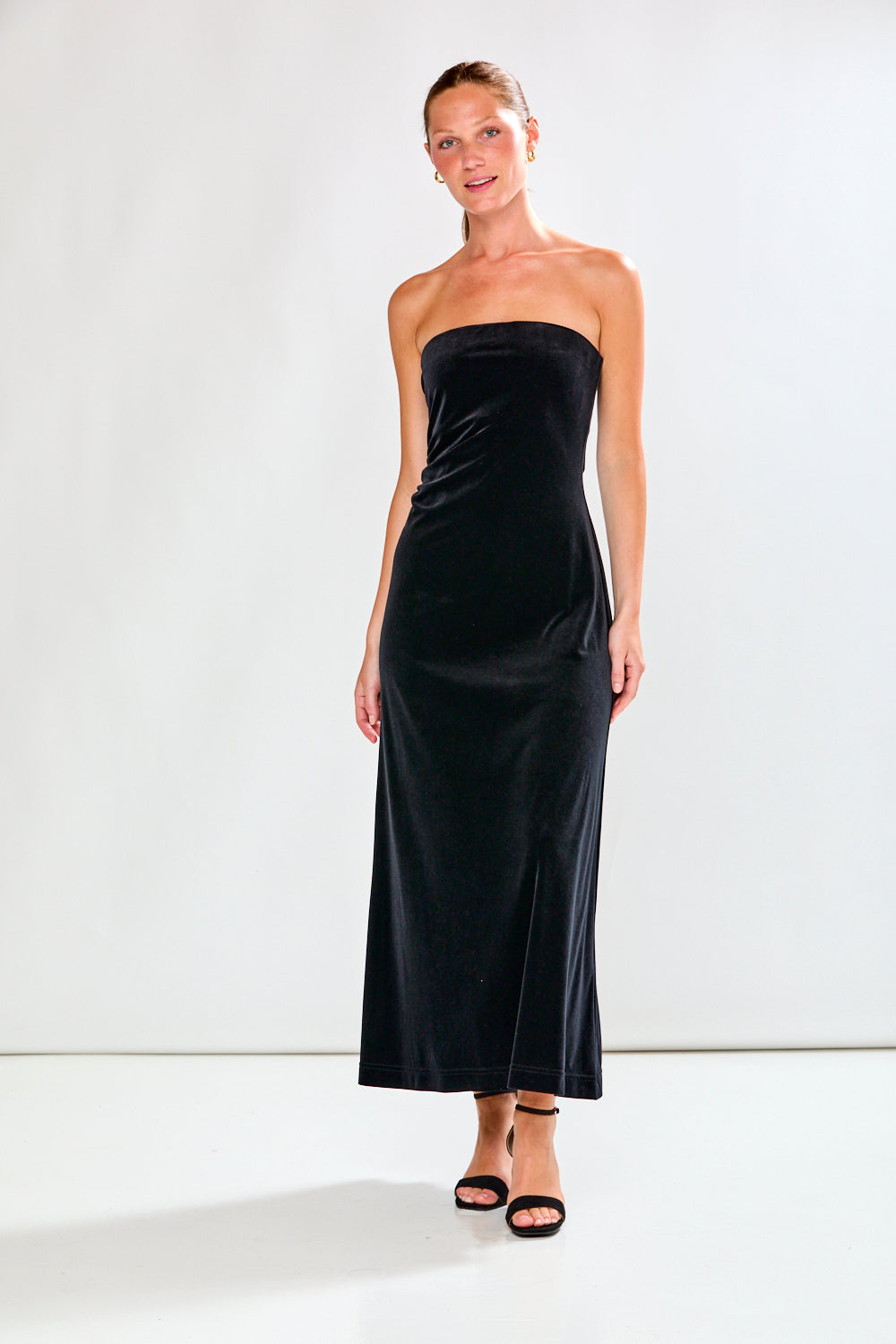 Woman wearing a black strapless dress against a white background