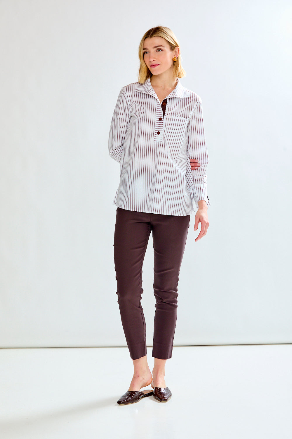 Woman wearing a striped shirt and brown pants on a white background
