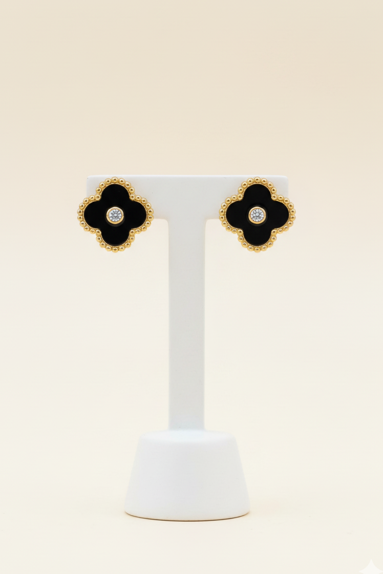 Photo of a par of black clover studs on an earring stand