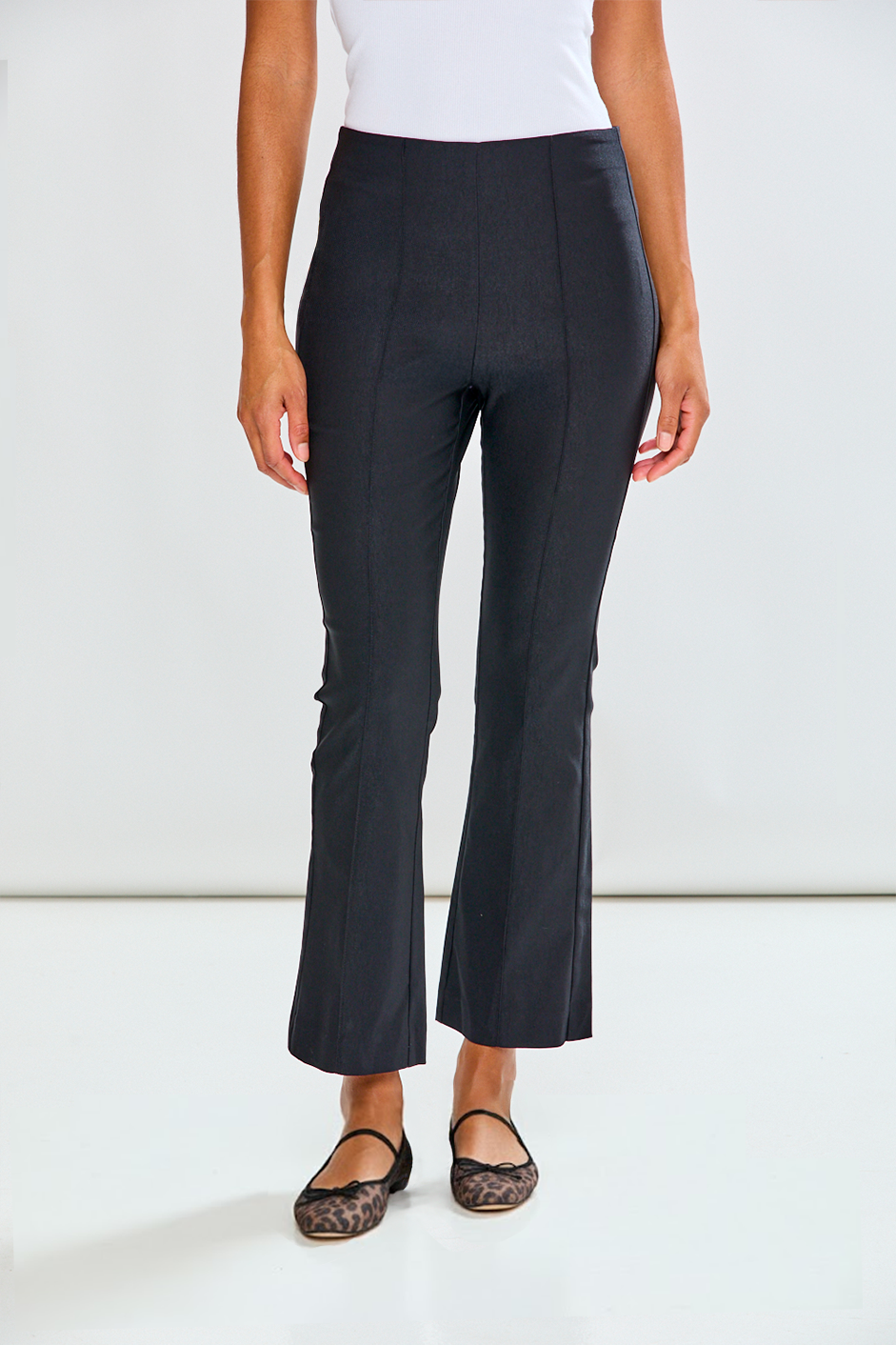 Person wearing black flared pants on a white background