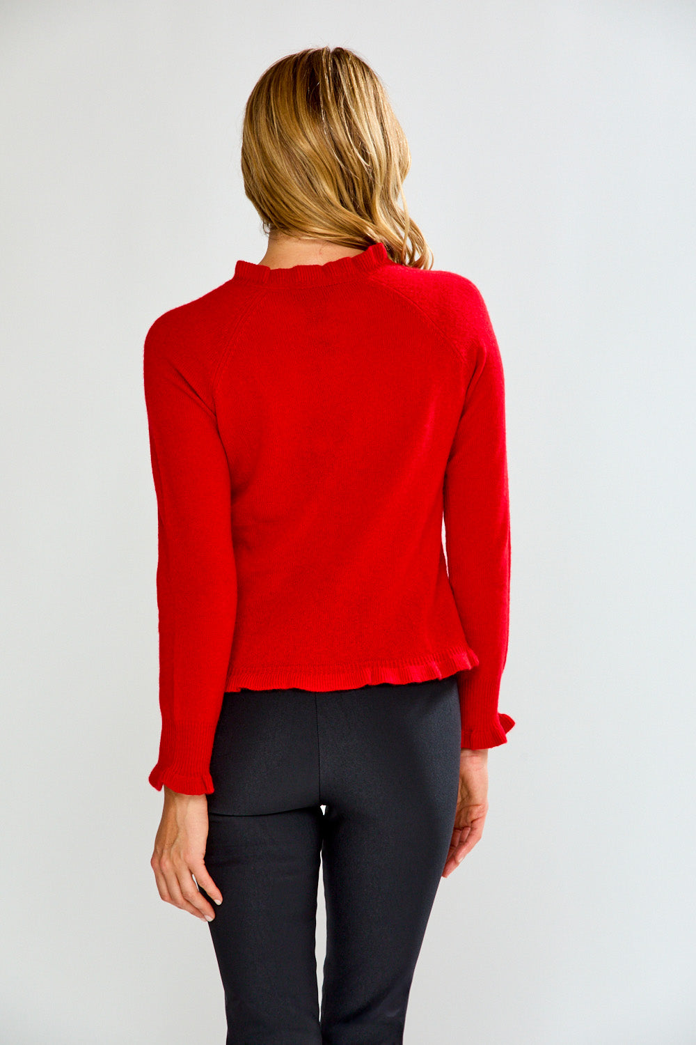 Person wearing a red sweater and black pants on a plain background