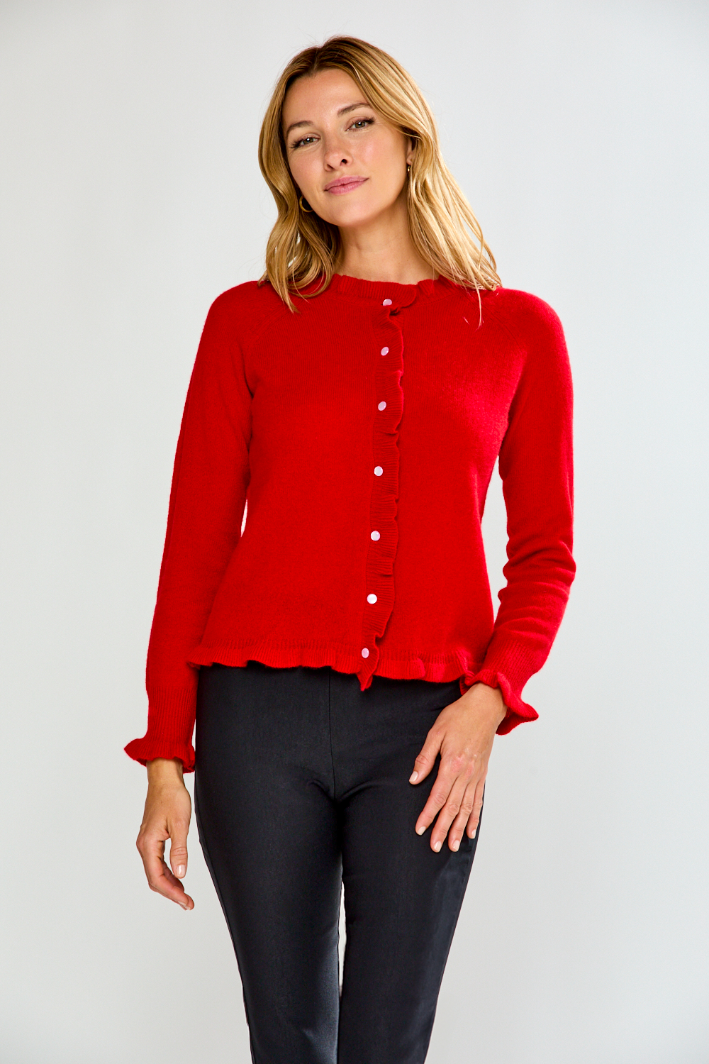 Woman wearing a red cardigan and black pants on a white background
