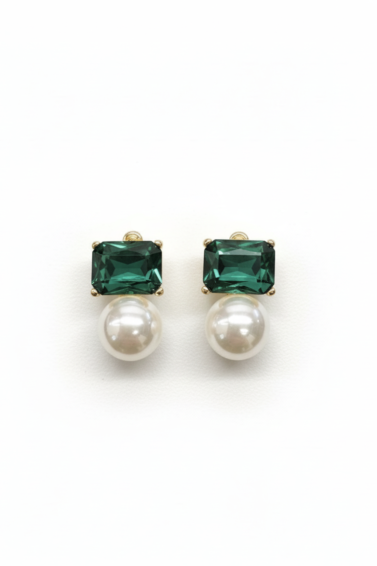 Pair of earrings with green gemstones and pearl-like bottoms on a white background