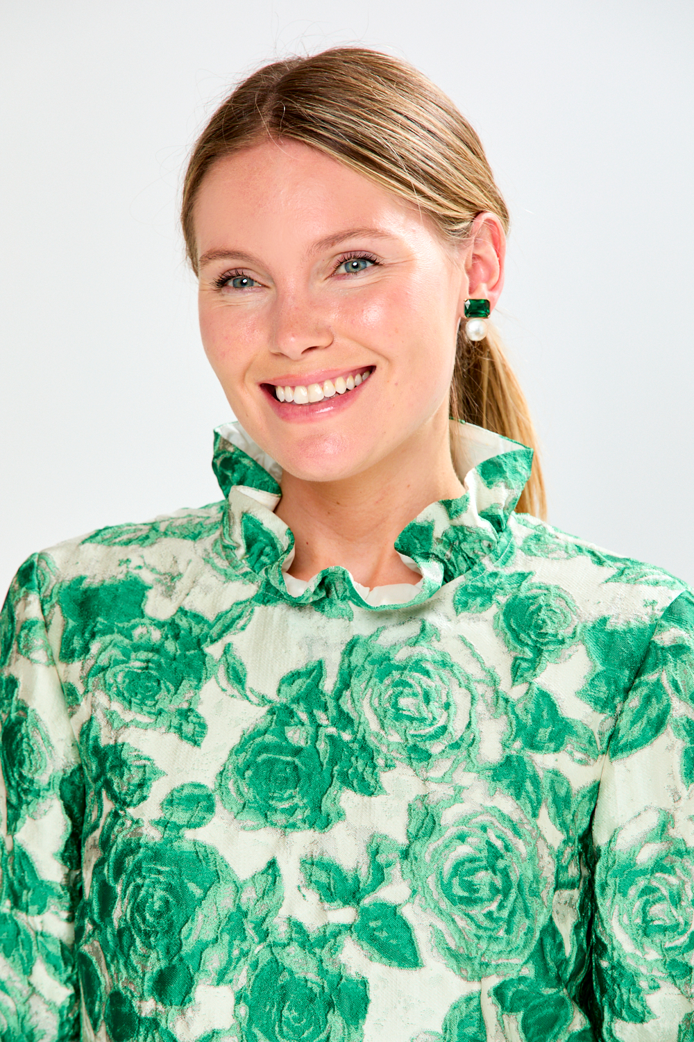 Woman wearing a green floral patterned blouse against a white background
