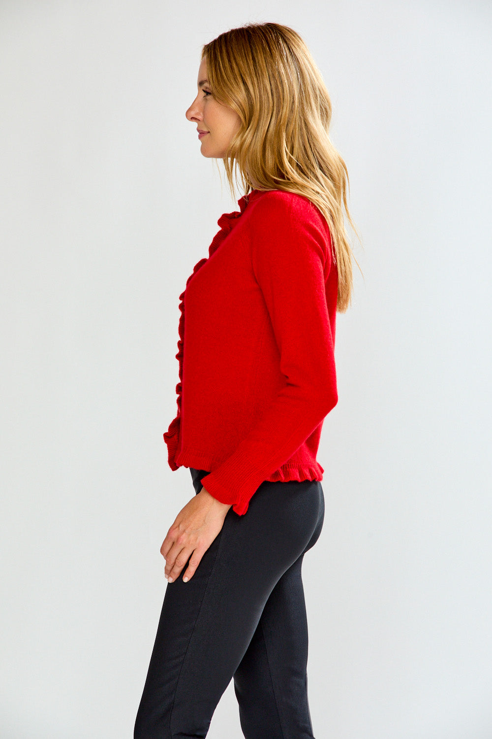 Woman wearing a red blouse and black pants against a white background