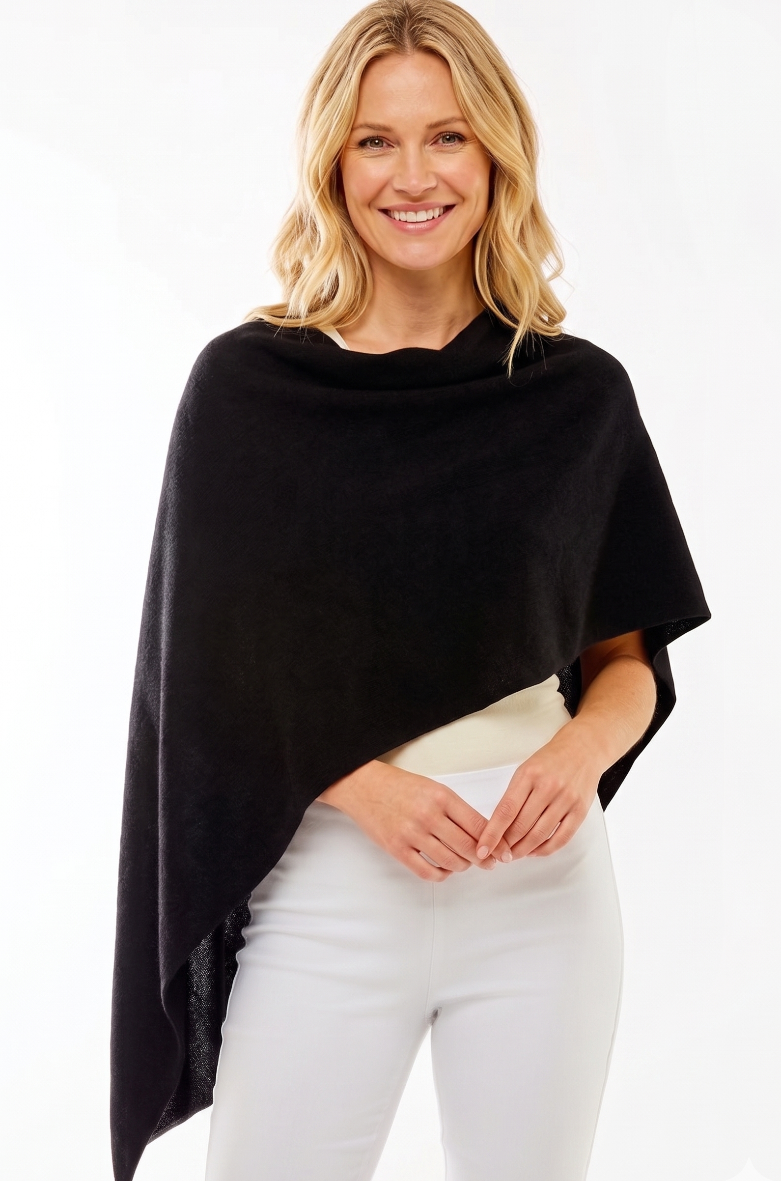 Woman wearing a black poncho over a white outfit on a white background