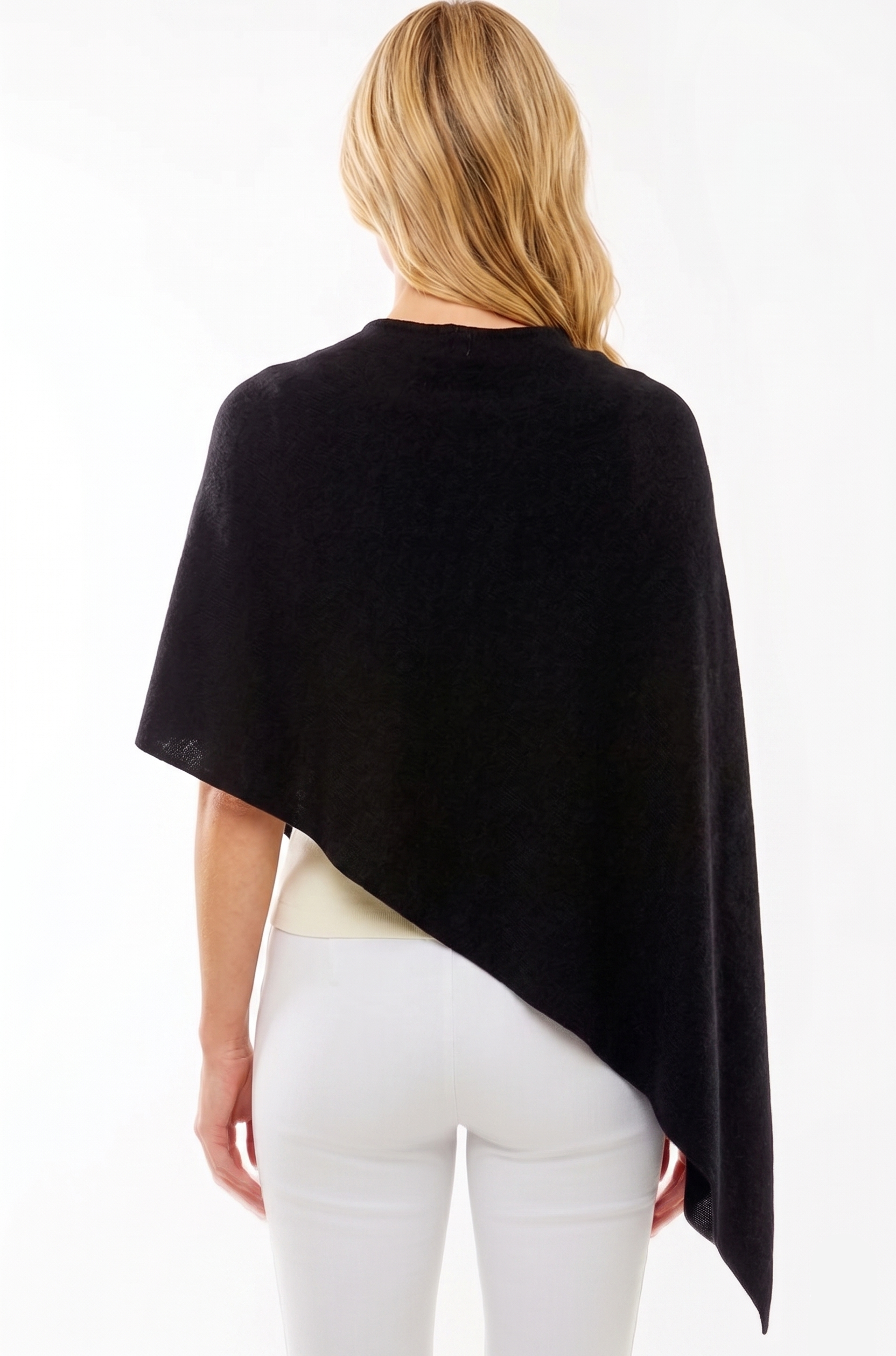 Woman wearing a black poncho over a white outfit on a white background