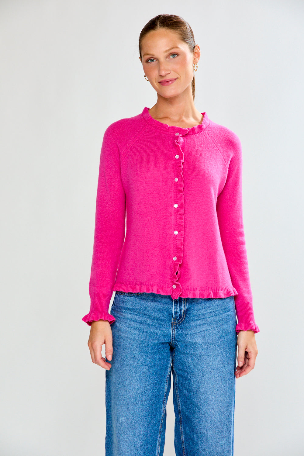 Woman wearing a Fuchsia cardigan and blue jeans on a white background