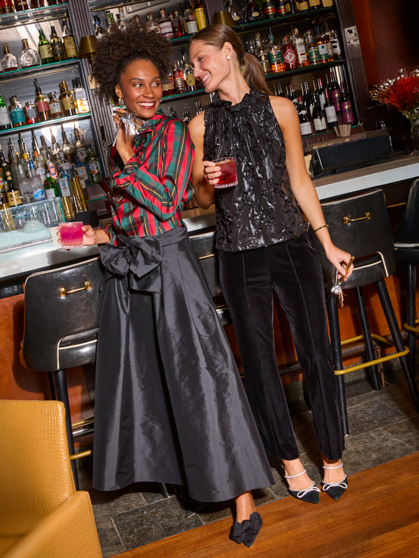 Women wearing holiday attire while standing at a bar