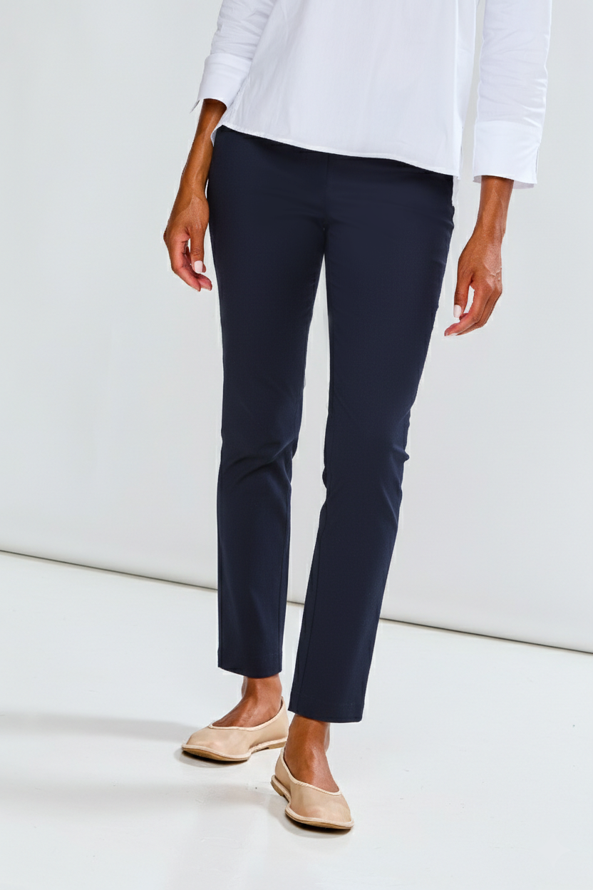 Person wearing navy pants and a white top on a light background