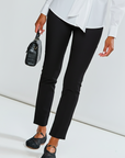 Person wearing a white blouse, black pants, and black shoes on a white background