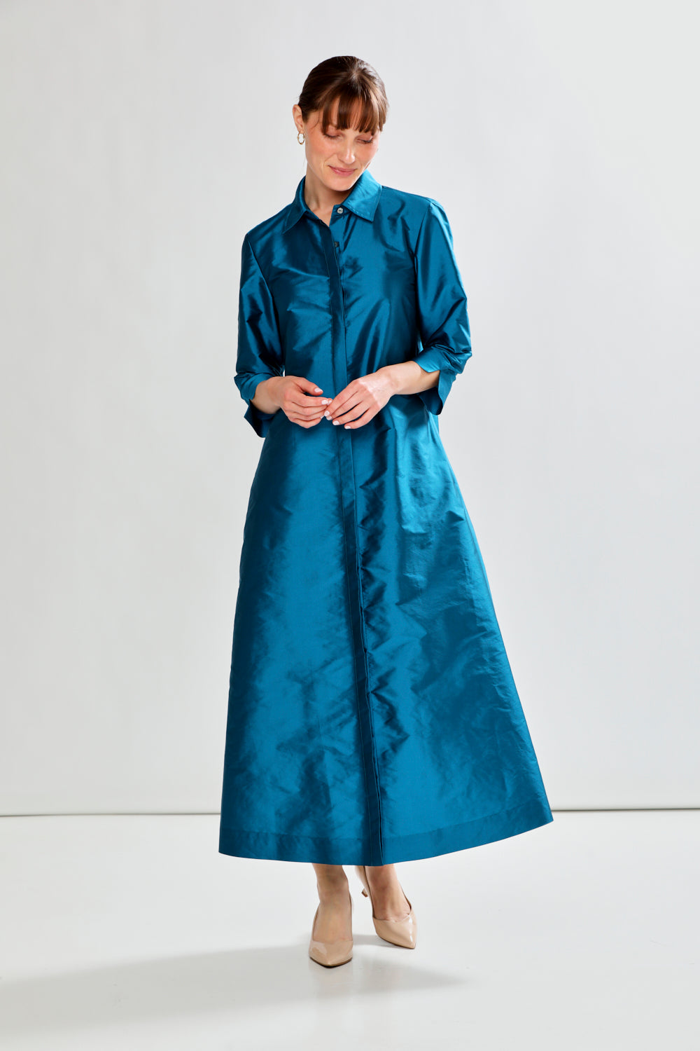 Woman wearing a long blue dress against a white background
