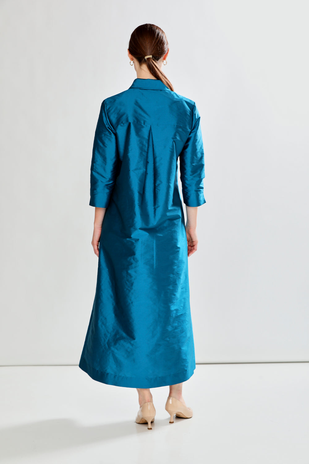 Woman wearing a long blue dress against a white background