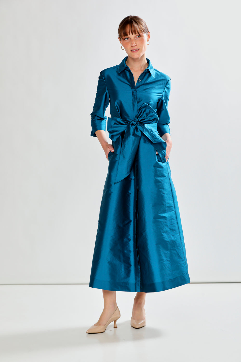 Woman wearing a blue dress with a belt against a white background