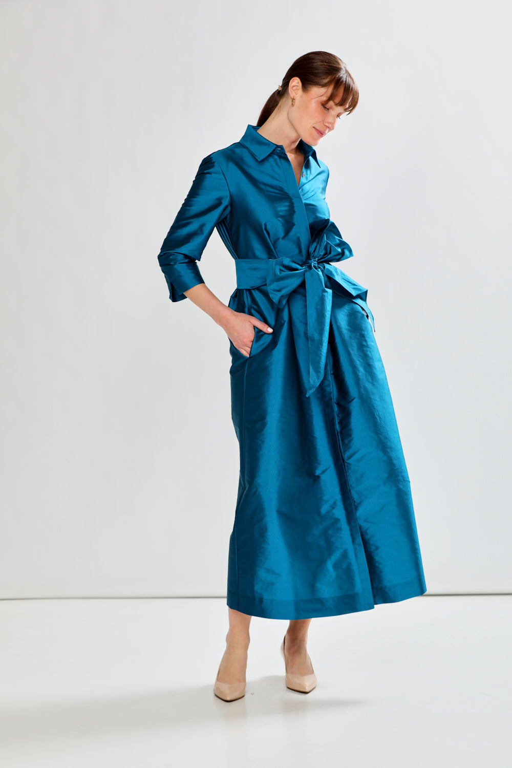 Woman wearing a blue dress with a belt on a white background
