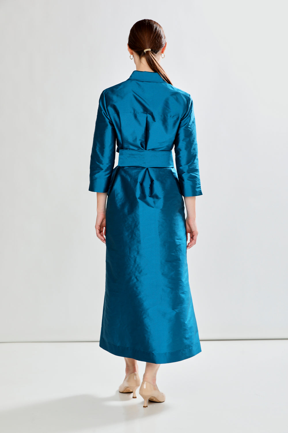 Woman wearing a blue dress with a belt against a white background