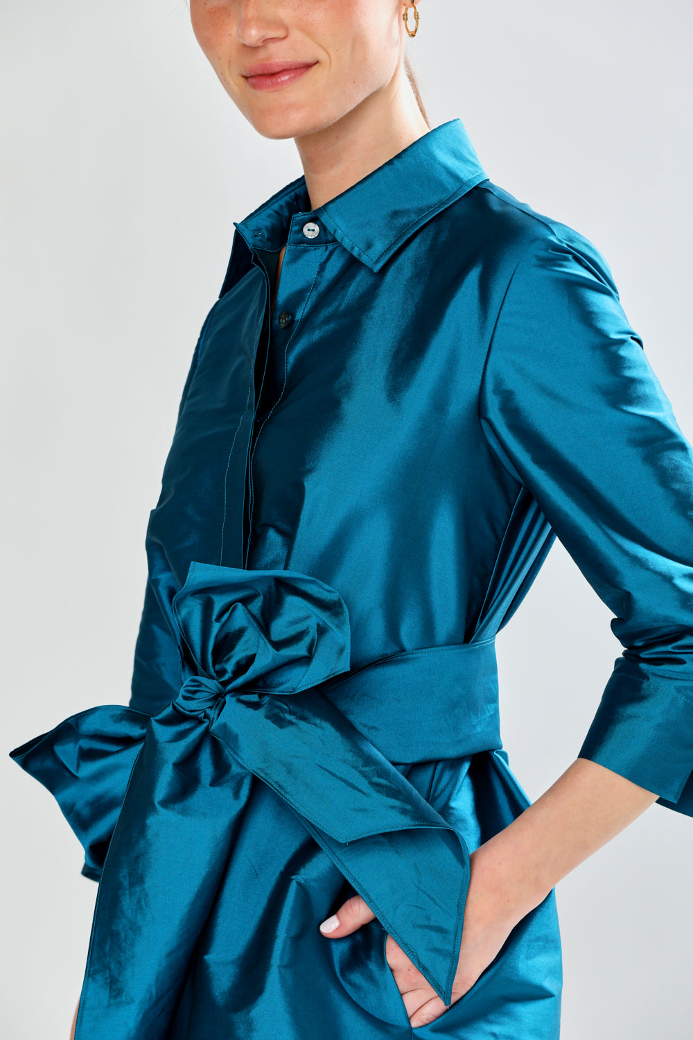 Woman wearing a blue dress with a large bow detail on a light gray background