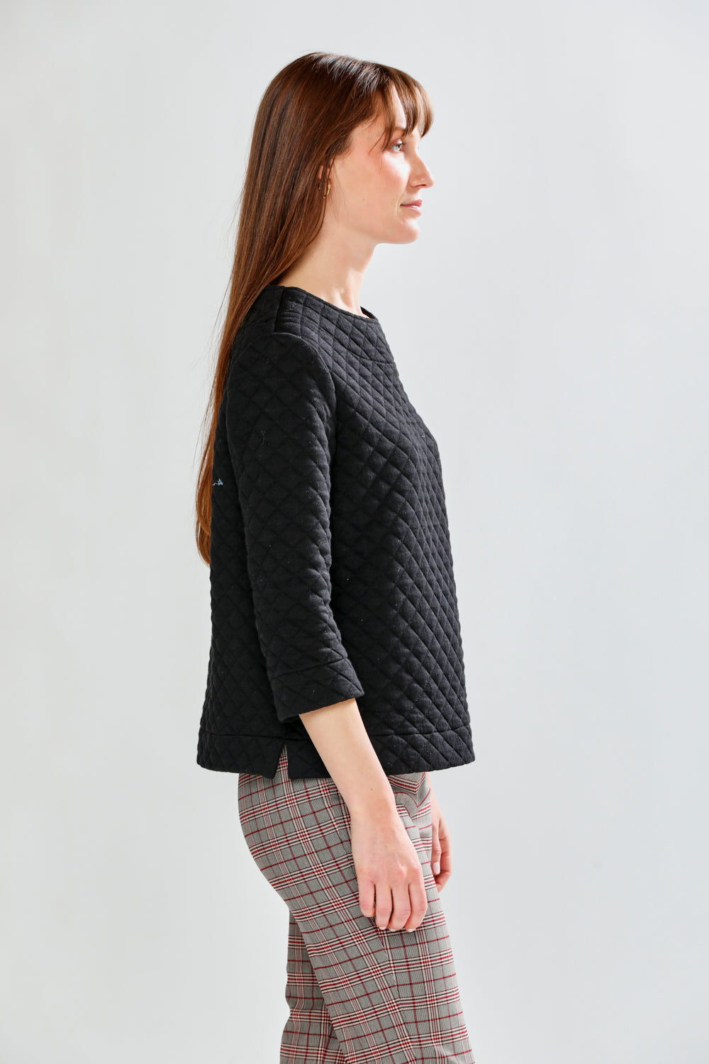 Woman wearing a black quilted pullover on a white background