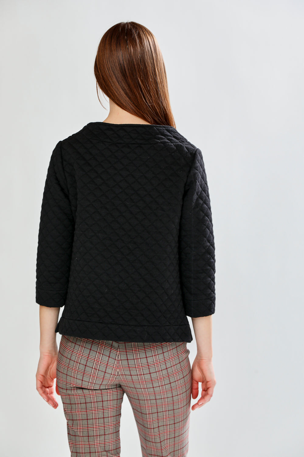 Person wearing a black quilted pullover on a white background
