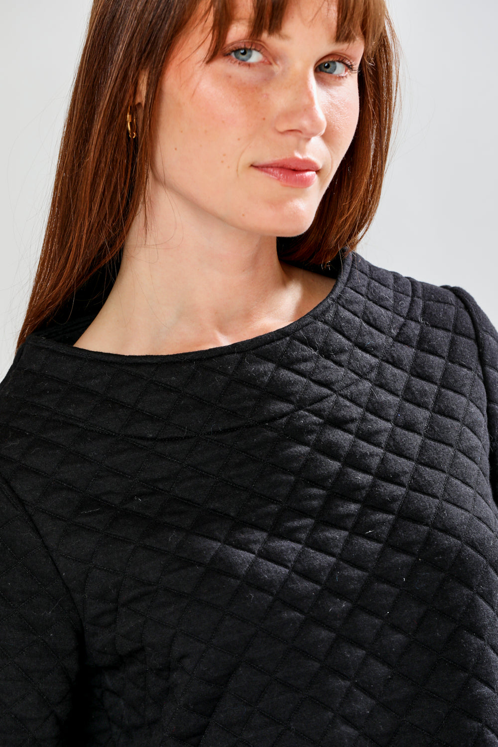 Person wearing a black quilted pullover against a plain background