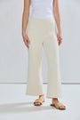 Person wearing beige wide-leg pants and a white top on a plain background