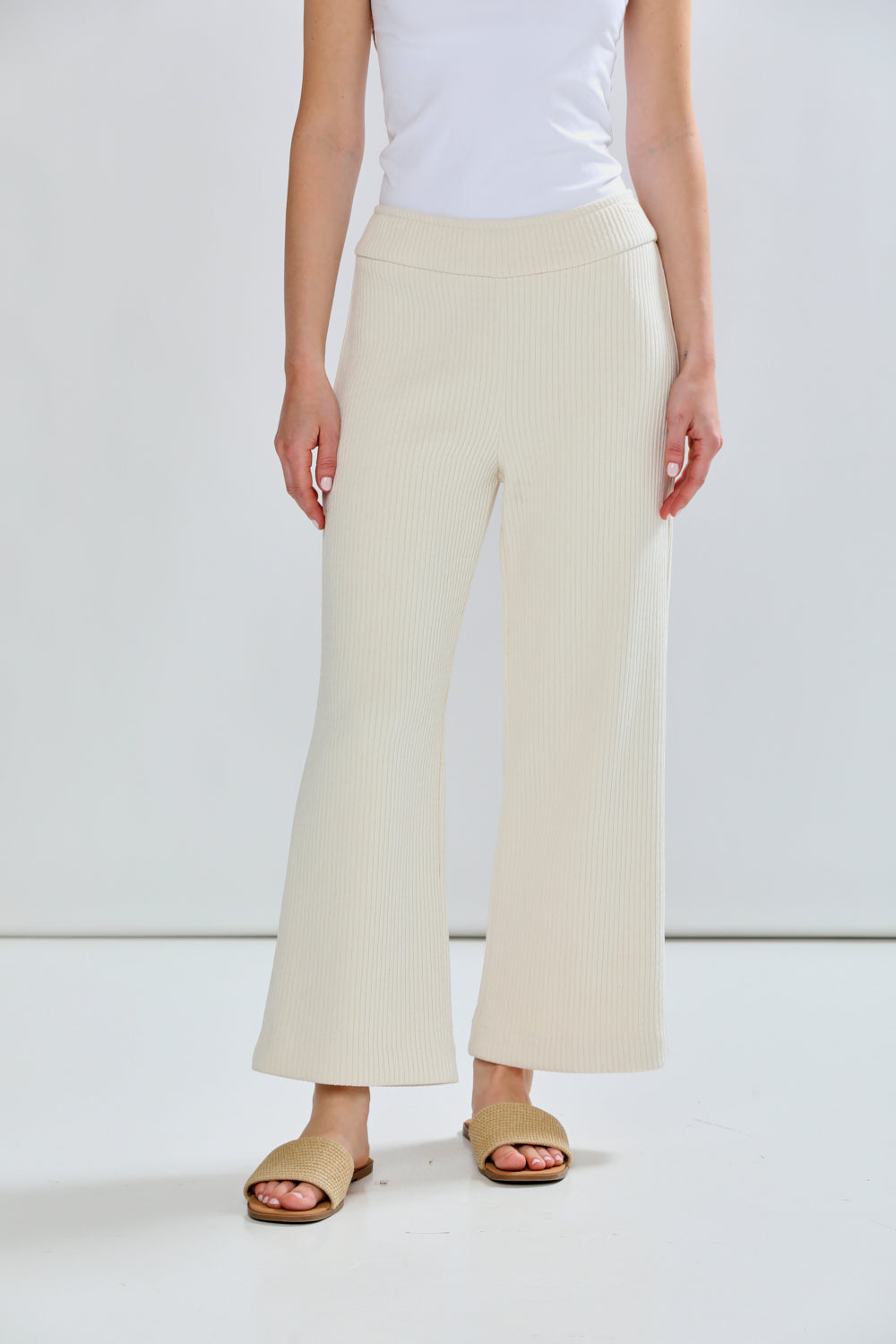 Person wearing white top and cream-colored wide-leg pants on a plain background