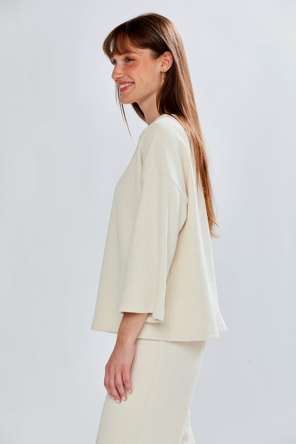 Woman wearing a light-colored outfit against a plain background