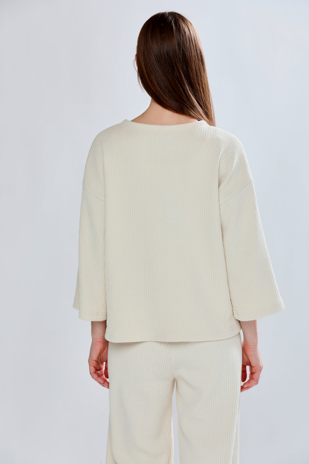Woman wearing a cream-colored outfit against a white background