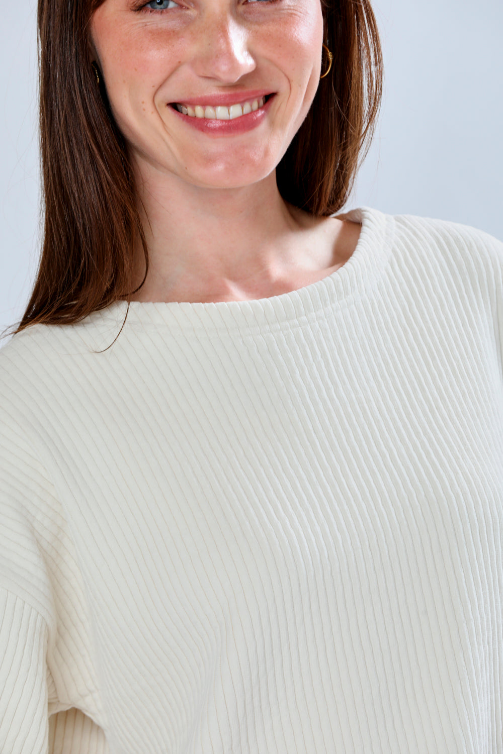 Woman wearing a white sweater against a light background