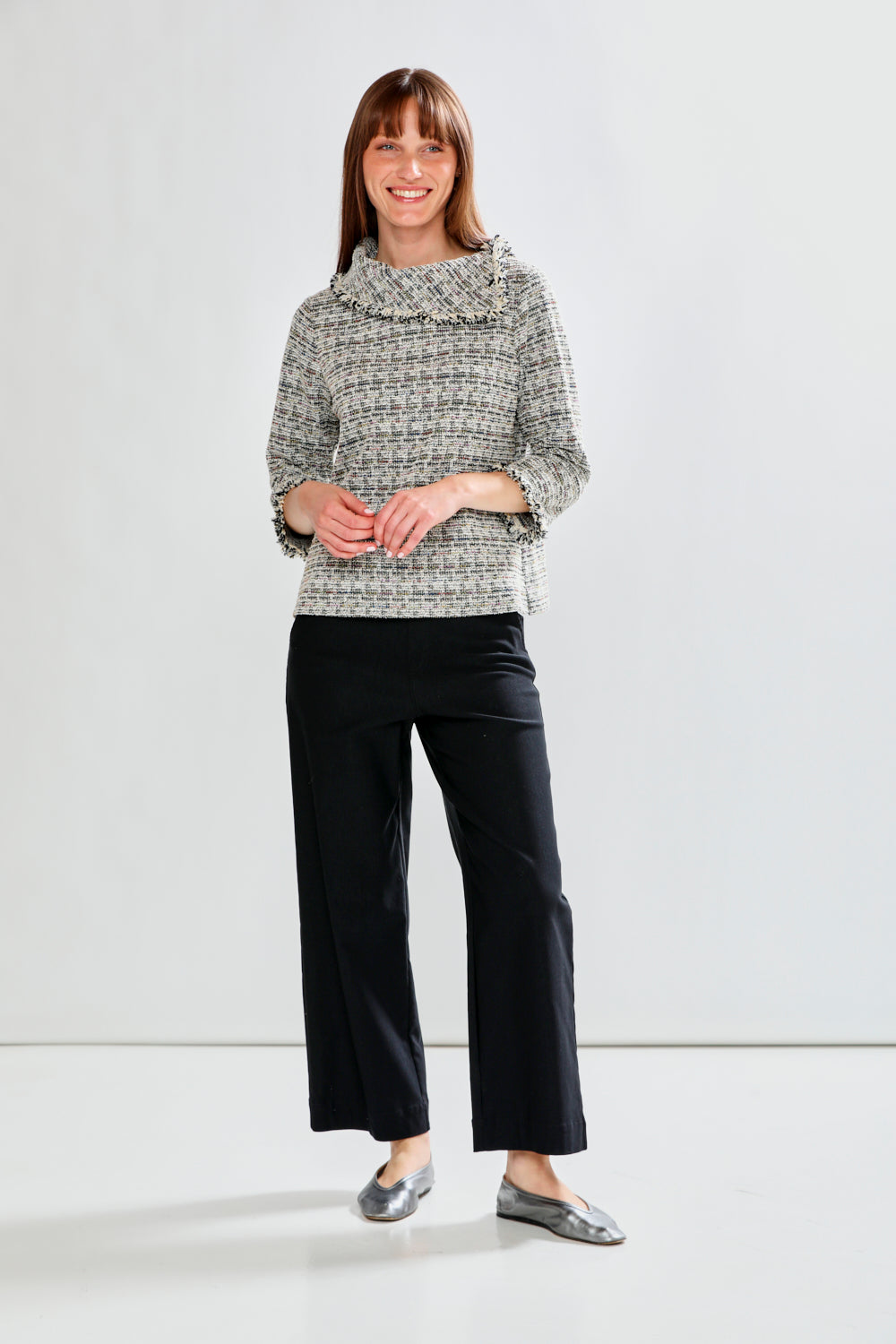 Woman wearing a patterned blouse with fringe collar against a white background